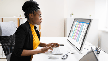 Woman-working-on-spreadsheets-on-desktop-computer
