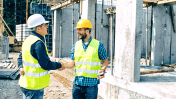 Two-men-in-high-visibility-vests-shaking-hands-on-construction-site