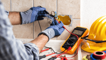 Gloved-electrician-hands-working-on-wires-from-an-outlet